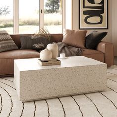 a living room with a couch, coffee table and rugs on the floor in front of large windows