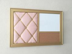 a pink and gold mirror hanging on the wall next to a white wall with two pictures in it