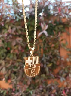 a gold plated necklace with a soccer emblem hanging from it's center chain