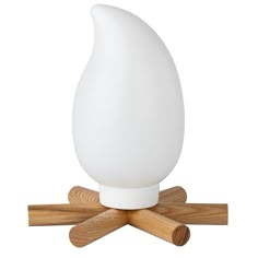 a white table lamp sitting on top of wooden sticks in front of a white background