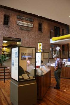 a man standing in front of a display case filled with lots of books on top of a hard wood floor