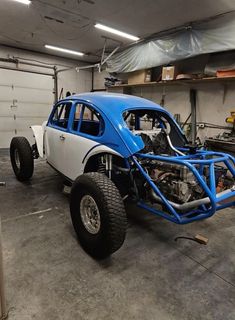 a blue and white buggy parked in a garage next to another car on the ground