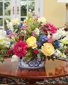 a vase filled with colorful flowers on top of a wooden table