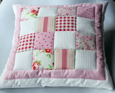 a pink and white patchwork pillow sitting on top of a table