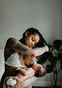 a woman holding a baby in her arms while she is breastfeeding it's head