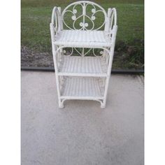 a white wicker chair sitting on top of a cement ground next to a grass field