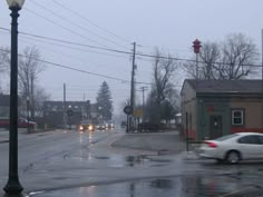 a white car driving down a wet street next to a light pole and traffic lights