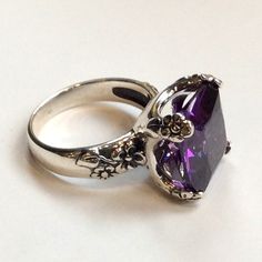 "Hello spring Chunky and fantastic ring, so unique you will never want to take it off. Amazing floral design of such a statement piece with a beautiful Amethyst stone. R2272-2 © 2011 Artisanimpact Inc. All rights reserved. Construction & Dimensions: Sterling silver, clear quartz or lab created amethyst/garnet. Approximate stone size: 14mm (0.55\") x 14mm (0.55\") Please indicate your size in the order. About our jewelry Silvercrush features botanical and organic collection designed and made Open Ring With Large Stone For Anniversary, Elegant Amethyst Open Ring For Wedding, Elegant Large Stone Crystal Wedding Ring, Elegant Open Amethyst Ring For Wedding, Elegant Cushion Cut Cluster Ring Gift, Elegant Cushion Cut Cluster Ring As Gift, Cushion Cut Rings For Formal Occasions, Anniversary Rings With Large Stone And Open Ring Design, Classic Large Stone Promise Ring