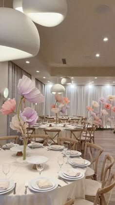 a banquet room set up with white table cloths and pink flowers