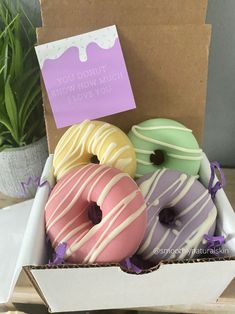 four donuts in a box with a note attached to the front and back side