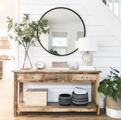 a wooden table topped with a mirror next to a lamp