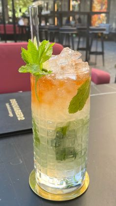 a glass filled with ice and mint sitting on top of a table