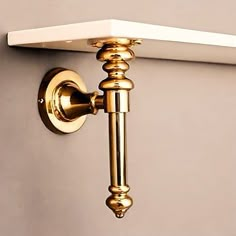 a close up of a wall light on a white shelf with a gold handle and knob