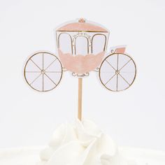 a pink and white cake topper with a horse drawn carriage on it's side