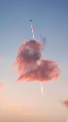 an airplane is flying in the sky with pink clouds