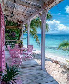 a porch with pink chairs and palm trees on the beach