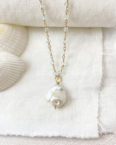 This elegant Baroque Pearl and Aquamarine Necklace is a luxurious statement piece featuring a large baroque pearl suspended on a chain of shimmering micro-faceted pale blue aquamarine gemstone beads, all handcrafted with beautiful gold fill. This coastal-inspired necklace is perfect for adding an elegant touch to any look, either solo or layered with other pieces. Necklace length: 16 inches plus 2 inch extender Materials: baroque pearl, aquamarine gemstone beads, gold filled clasp, wire and comp Unique Baroque Pearl Drop Jewelry, Briolette Pearl Jewelry With Natural Stones, Unique Pearl Drop Necklace For Wedding, Unique Wedding Pearl Drop Necklace, Baroque Pearl Teardrop Jewelry With Pearl Chain, Teardrop Baroque Pearl Chain Jewelry, Baroque Pearl Pendant Long Necklace, Baroque Pearl Necklace With Natural Stones As Gift, Handmade Pearl Necklace With Briolette Shape