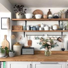 a kitchen with white cabinets and wooden shelves