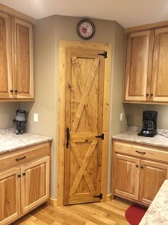 a kitchen with wooden cabinets and a clock on the wall above the door, along with granite counter tops