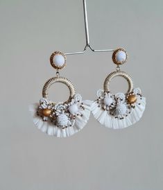 "Boho Handmade Raffia embellished white and gold wedding hoop earring. These boho wedding earrings are one of the most beautiful and one of the rare workmanship on any handmade earrings. The hoop earrings are made of multiple elements like tiny seed beads of white, gold, and fringes of raffia. The tiny seed bead balls and flowers are made with patience and aligned to make them look great for Wedding Jewellery. The gold color is used as an accent. The Earrings measure about approx. 3.10\" long an Handmade Bohemian Wedding Jewelry, Bohemian Handmade Wedding Jewelry, Bohemian Beaded Flower Earrings For Wedding, White Bohemian Flower Earrings For Wedding, White Round Chandelier Earrings For Party, Bohemian Bridal Earrings For Wedding, Elegant Handmade Hoop Beaded Earrings, Bohemian Hoop Earrings For Wedding, Handmade Round Flower Earrings For Wedding