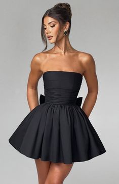 THE dress of the season has landed and you're going to be obsessed. Meet Katrina, our dreamy mini with a pretty, voluminous skirt and waist cinching bodice. Fastening with a zip to the back, tie with an oversized bow to complete the look for perfect feminine drama. 



Colour: Black.

Premium non-stretch cotton blend fabric.

Fully lined.

Strapless ruched bodice with boning.

Waist cinching.

Oversized tie to create bow detail to back.

Voluminous skirt with tulle lining.

Zip fastening to the Evening Dress With Gathered Full Skirt, Evening Ruched Dress With Fitted Waist, Evening Dress With Ruched Fitted Waist, Elegant Fitted Dresses With Bubble Hem, Mini Length Pleated Bodice Dress For Night Out, Mini Dress With Pleated Bodice For Night Out, Elegant Black Dress With Gathered Waist, Prom Mini Dress With Ruched Bodice, Black Party Dress With Gathered Skirt