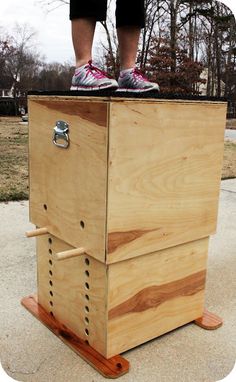 a person standing on top of a beehive with their feet on the frame