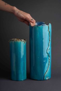 two blue vases that have been made to look like they are being held by someone's hand