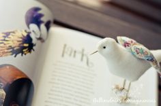 a white bird figurine sitting on top of an open book next to decorative objects