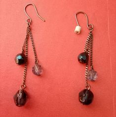 two pairs of dangling earrings on a red surface