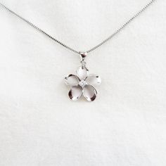 Introducing our exquisite Silver Plumeria Flower Necklace, a stunning piece that encapsulates the beauty of nature. This captivating necklace features a meticulously crafted Plumeria flower pendant adorned with sparkling Cubic Zirconia, adding a touch of brilliance to your look. The silver finish exudes elegance and sophistication, making it a perfect accessory for any occasion. The necklace comes with an 18-inch Rhodium Plated Box Chain, ensuring a comfortable and secure fit. Rhodium plating pr Mother's Day White Gold Jewelry With Flower Charm, Silver Flower Shaped Jewelry For Mother's Day, Nickel-free Flower Pendant Jewelry For Mom, Nickel-free Flower Pendant Jewelry Gift For Mom, Nature-inspired White Flower Pendant Jewelry, Silver Flower Necklace For Anniversary, Delicate Silver Jewelry For Mom, Delicate Silver Jewelry Gift For Mom, White Gold Flower Shaped Necklace