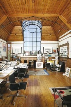 an office with wooden floors and large windows in the ceiling, along with lots of desks