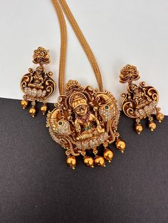 CZ Goddess Lakshmi Nakshi Matte Finish Pendent Set It comes with Complimentary Matte Chain but can be used with any gold chain or beads. Pair it up with Saree or any Indian Attire Pendent Length Approx. 3 Inches Pearl Mala Length : Approx. 16  Inches;  Earring Length : Approx. 2 Inches; Push back. Comes in gift box, Ideal for gifting too. Ready to ship from Boston, MA Delivery time 3-5 days. If you have any questions please let me know. Thank you!! 22k Gold Temple Jewelry Sets As Gift, Gold Kundan Jewelry Set With Peacock Design, Diwali Temple Jewelry Sets With Pendant, Gold Pendant Jewelry For Navratri, Gold Plated Temple Jewelry Set For Puja, Heavy Gold Jewelry For Navratri, Gold Plated Temple Jewelry Sets, Gold Temple Jewelry Sets With Tilla, Gold Temple Jewelry Set With Peacock Design