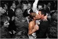 a bride and groom kissing in front of a crowd