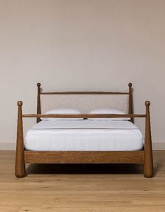 a wooden bed frame with white sheets and pillows