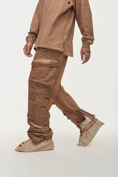 The Distressed Multi-Pocket Layered Cargo Pants in Earth perfectly merge street style with practicality. These cargo pants feature multiple flap pockets on both sides, providing ample storage and a rugged look. The elasticized cuffs create a natural stacking effect when worn, while zippers on the cuffs allow for an adjustable fit around the calves, enhancing mobility. The washed, distressed finish adds a unique edge to the design. Made from premium 100% cotton fabric, these slightly oversized pa Full-length Techwear Cargo Jeans With Hip Pockets, Utility Brown Cargo Jeans With Patch Pockets, Brown Utility Cargo Jeans With Patch Pockets, Baggy Brown Cargo Pants With Cargo Pockets, Utility Parachute Pants With Flap Pockets For Outdoor, Brown Straight Leg Cargo Pants With Pockets, Baggy Cargo Jeans With Hip Pockets For Outdoor, Baggy Brown Cargo Pants With Side Pockets, Outdoor Utility Parachute Pants With Flap Pockets