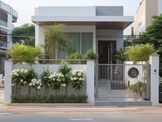 a house with white flowers and greenery on the front wall, along with a gate