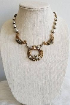 This is a vintage 1940s Original by Robert necklace. The necklace features a gold tone intricate metalwork with flowers and pearl tone details. The pearl tone beads are likely baroque style hand-painted glass given the era. The pearl tone beads range from brighter white to champagne to gray depending on the bead. The range of color could be intentional in design or from previous age and wear. The back of the center circle is signed on a palette shape. This necklace is in excellent condition.Cent Gold Beaded Pearl Necklace For Evening, Antique Beaded Jewelry For Evening, Vintage Gold Jewelry With Gold Beads, Vintage Gold Beaded Necklaces For Wedding, Vintage Beaded Necklaces For Anniversary, Gold Beaded Bridal Necklace For Anniversary, Anniversary Gold Beaded Bridal Necklace, Antique Pearl Jewelry For Weddings, Antique Beaded Necklaces For Evening