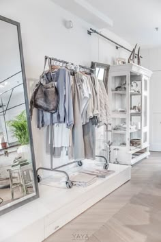 a clothing rack with clothes hanging on it and a mirror in the corner next to it