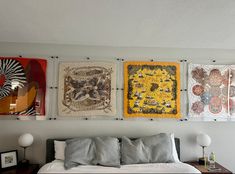 a bed sitting under three paintings on the wall