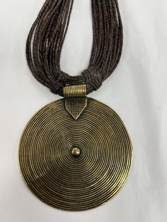 A beautiful handmade brass pendant from Ghana hangs on a hand weaved leather. The necklace is a collectible art and would be perfect for adding to your African jewelry collection or a major statement piece to wear. Black African Necklace, Antique Gold Medallion Jewelry In Copper, Antique Gold Copper Medallion Jewelry, Antique Gold Medallion Copper Jewelry, Bronze Brass Jewelry With Coin Pendant, Antique Finish Copper Medallion Jewelry, Bohemian Jewelry With Antique Finish Round Pendant, Handmade Antique Gold Medallion Necklace, Artisan Gold Jewelry With Adjustable Cord