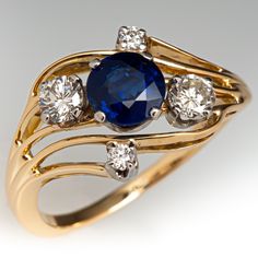 This beautiful ring is centered with a round mixed cut sapphire, weighing 1.00 carats, in a four-prong setting. The top of the ring is four-prong set with four (4) round brilliant cut diamonds. The ring measures 11.2mm at the top, rises 5.4mm above the finger, tapering to 1.5mm wide and 1.0mm thick at the base of the shank. The ring is currently a size 6.25. Blue Engagement Ring, Round Sapphire, Sapphire Engagement Ring Blue, Sapphire Diamond Ring, Sapphire Engagement, Sapphire Diamond, Jewelry Rings Engagement, Blue Rings, Engagement Rings Sapphire