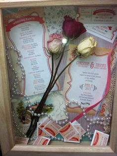 a wooden frame with some flowers and other items in it on a table or shelf