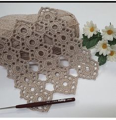 a crocheted doily next to some daisies