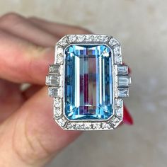 This beautiful ring features an approx 11.86-carat emerald-cut aquamarine bezel set within a handcrafted platinum mounting. The aquamarine is flanked by three baguette cut diamonds on each side and surrounded by a halo of round brilliant cut diamonds. Additional round brilliant cut diamonds are set along the shoulders. The total diamond weight is approx. 0.81 carats. This ring is decorated with fine milgrain and an openwork under-gallery. ✦ AQUAMARINE SPECIFICATIONS:    Aquamarine Cut: Emerald C Luxury Gia Certified Emerald Cut Gemstones, Luxury Gia Certified Aquamarine Ring, Luxury Topaz Ring Emerald Cut With Vvs Clarity, Luxury Emerald-cut Topaz Ring With Vvs Clarity, Luxury Aquamarine Octagon Ring, Gia Certified Emerald Cut Topaz Ring In Platinum, Luxury Gia-certified Emerald Cut Topaz Ring, Gia Certified Emerald Cut Platinum Topaz Ring, Emerald Cut Platinum Gemstones For Gifts