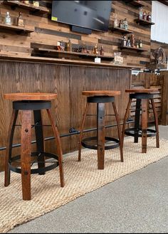 three wooden stools sitting in front of a bar with a tv on the wall