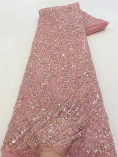 a pink dress with sequins on it is being held up by someone's hand