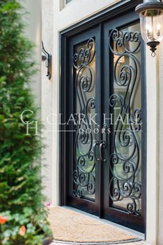 an ornate iron door is shown in front of a house with two lamps on either side