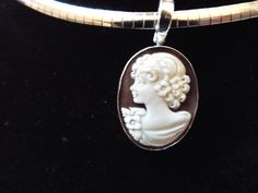 "This is a hand carved sardonyx cameo measuring 20 mm (0.79\") by 25 mm (0.98\") set in sterling silver. Bail is an enhancer of 5 mm in size, so it will accommodate a chain up to 4 mm (0.15\"). This cameo is a carved portrait of a women by Sorriso. It is absolutely beautifully carved and it comes packed in a black velvet box and certificate of authenticity for gift giving. Chain included. Welcome to CASCO Cameos, LLC. CASCO Cameos is the sole provider of cameos in North America. The founding com Silver Cameo Round Pendant Jewelry, Silver Cameo Jewelry With Round Pendant, Collectible Cameo Jewelry With Round Pendant, Collectible Cameo Round Pendant Jewelry, Silver Cameo Round Jewelry, Silver Cameo Oval Pendant Jewelry, Silver Oval Cameo Pendant Jewelry, Oval Cameo Sterling Silver Jewelry, Formal Oval Sterling Silver Cameo Jewelry