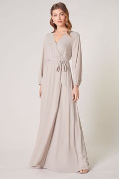 Warm and inviting, the Wholehearted Maxi Dress is a perfect combination of modest and sultry. Long balloon sleeves frame a surplice neckline separated by a tie at the waist, creating a forgiving faux wrap. The skirt maintains an airy and flowy shape that trails behind as you walk down the aisle. - Chiffon- Faux wrap- Keyhole- Elastic waist- Comes in 14 ColorsSize + Fit - Model is 5'9" and wearing size XS- Measurements taken from size S - Chest: 35"- Length: 63 1/4" Fabric Self: 100% PolyesterLin Flowy V-neck Dress With Surplice Neckline For Date Night, Fall V-neck Belted Maxi Dress, Fitted V-neck Maxi Dress With Tie Waist, Formal Fall V-neck Wrap Dress, Modest Fitted V-neck Maxi Dress, Chic Fall Maxi Dress With Surplice Neckline, Elegant Maxi Wrap Dress For Brunch, Elegant Maxi Length Wrap Dress For Brunch, Flowy Faux Wrap Dress For Spring