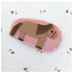 a felt horse brooch with pink and brown trim on it's back side